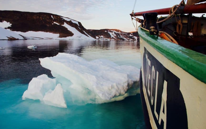 Tecla sailing through icy waters on a Classic Sailing adventure holiday. The nameplate of the ship with the green capping rail can be seen in the bright light as the ship slowly noses through the ice,