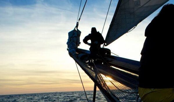 Schooner Twister crew member on the bowsprit in the sunrise